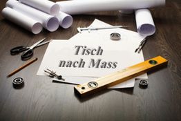 Werkzeug und Zeichnungen auf einem Tisch mit dem Text "Tisch nach Mass".