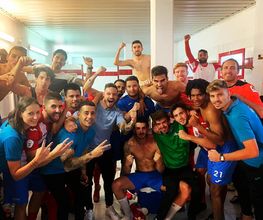 Grupo de personas celebrando en un vestuario. Algunos visten ropa deportiva.