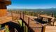 Wooden deck with mountain view, tables, and chairs under a clear blue sky.