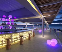 Bar al aire libre iluminado en tonos morados, con vista al cielo nocturno y luces decorativas.