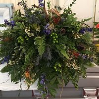 A lush, green floral arrangement with hints of purple and white blooms.