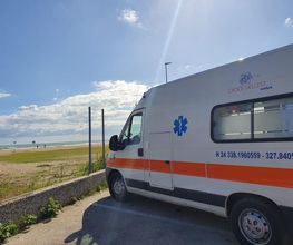 Ambulanza parcheggiata vicino al mare sotto un cielo sereno e soleggiato.