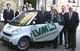 Menschen stehen neben einem Smart-Auto mit LVM Versicherungen Logo vor einem Backsteingebäude.