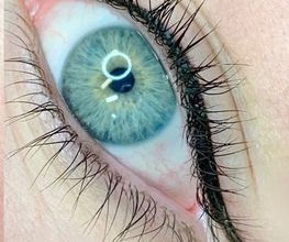 Close-up van een blauw oog met lange wimpers en donkere eyeliner.