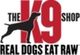 Silhouette of a dog with "The K9 Shop" and "Real Dogs Eat Raw" text.