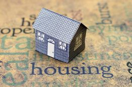 Paper house model on words related to housing.