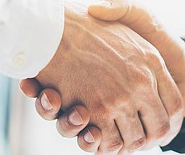 Zwei Personen geben sich die Hand, symbolisiert Vertrauen und Vereinbarung.