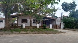 Casarão cercado por árvores, com varanda e portão de madeira em frente a calçada de pedra.