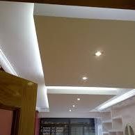 Teto com iluminação embutida moderna e luminárias LED acesas em uma sala ampla.