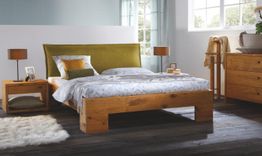 Holzbett in modernem Schlafzimmer mit Nachttischen und Lampen, helle Wände und Parkettboden.