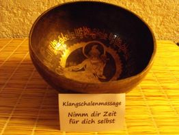 Klangschale mit Gravur auf Bambusmatte, Schild: "Klangschalenmassage - Nimm dir Zeit für dich selbst".
