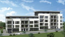 Mehrfamilienhaus mit hellen Fassaden und Balkonen, umgeben von Grünflächen und blauem Himmel.