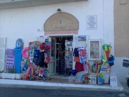 Negozio estivo con giochi da spiaggia e galleggianti appesi fuori, porta aperta.