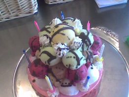 Bunter Eiskuchen mit Kerzen und Sahnehäubchen, dekoriert mit Schokoladensauce.