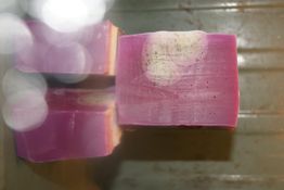 Zwei Stücke lila Seife mit weißem Muster auf einer metallischen Oberfläche.