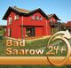 Rotes Haus mit Schriftzug "Bad Saarow 24+" im Vordergrund.
