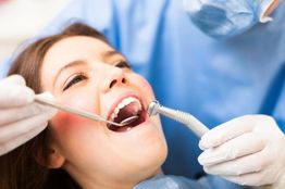 Woman at the dentist, open mouth, dental tools in use.
