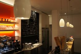 Moderne Cafeteria mit Tafelmenü, Kaffeemaschine und Eistüten auf einer Holztheke.