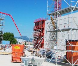 Baustelle mit Kränen und Gerüsten, blaue Himmel im Hintergrund.