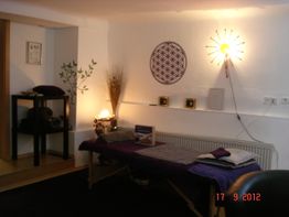 Massageraum mit Liege, Wanddeko und sanftem Licht, warmes und einladendes Ambiente.