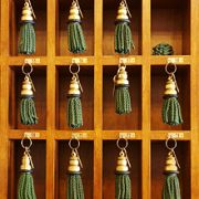 Wooden cubbies holding green tassel keychains, neatly organized in three rows.