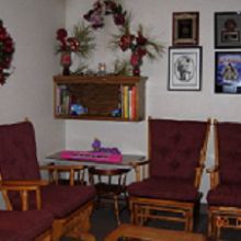 Cozy living room with maroon chairs, wall art, shelves with books, and floral decorations.