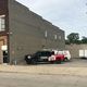 Two utility vans parked beside a brick building under a cloudy sky.