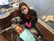 Dental hygienist with a masked smile, caring for a happy child in a dental chair.