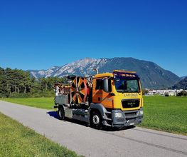 Lkw auf einer Straße vor Berglandschaft bei klarem Himmel.