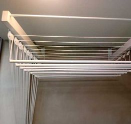 Varal de teto retrátil com várias cordas brancas em uma área interna.