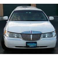 White sedan parked in front of green garage doors.