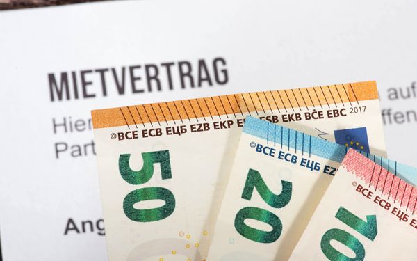 Ein Mietvertrag auf dem verschiedene Geldscheine liegen, die die zurückgezahlte Mietkaution sybolisieren.