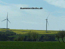 Zwei Windräder auf einer grünen Landschaft unter blauem Himmel, Schriftzug "hammerheiss.de".