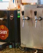 Máquina de chopp com torneiras em um balcão de bar, etiquetada como "Ashby".