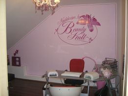 Nagelstudio mit lila Wanddekor, Tisch, Stühlen und Zubehör. Elegantes und gemütliches Ambiente.