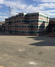 Pallet di scatole impilate all'aperto in un cortile sotto un cielo parzialmente nuvoloso.