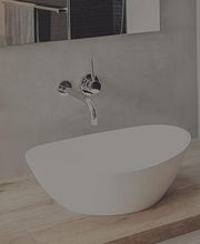 Modernes Waschbecken mit Wandarmatur auf Holzoberfläche.