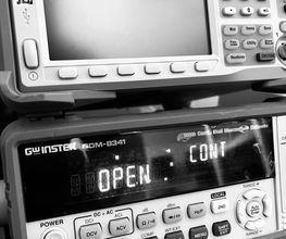 Elektronische Geräte im Schwarzweißfoto, eines zeigt "OPEN:CNT" auf dem Display.