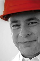 Porträt eines lächelnden Mannes mit rotem Bauhelm.