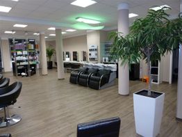 Moderner Friseursalon mit hellen Böden, Stylingstationen und Pflanzen in weißen Töpfen.