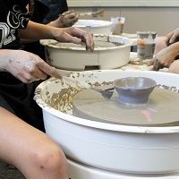 People working on pottery wheels with clay.