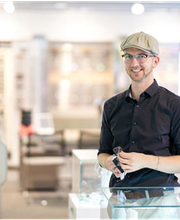 Ein Mann mit Mütze lächelt in einem modernen Brillengeschäft.