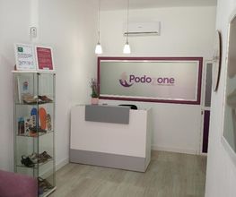 Recepción moderna de clínica podológica con estantería de zapatos y decoración sencilla.