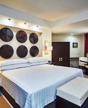 Habitación moderna con cama doble, decoración en la pared y cortinas rojas.