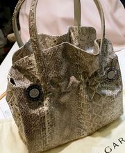 Luxuriöse Tasche mit Schlangenhaut-Optik, doppelte Henkel, auf einem Bvlgari-Stoffbeutel.