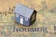 Paper house model on words related to housing.