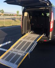 Furgoneta con rampa desplegada para accesibilidad en una carretera bajo cielo despejado.