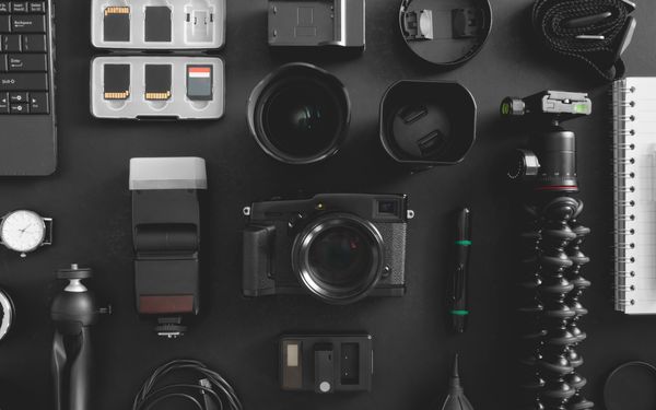 Verschiedenes Kamerazubehör liegt geordnet auf einer schwarzen Tischplatte.