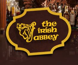 Letrero marrón y dorado con un arpa y texto "The Irish Abbey" sobre un fondo de botellas.