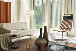 Sala moderna con muebles de diseño, jarrones, sofá blanco y gran iluminación natural.